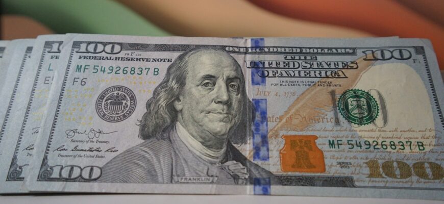 a stack of one hundred dollar bills sitting on top of a table