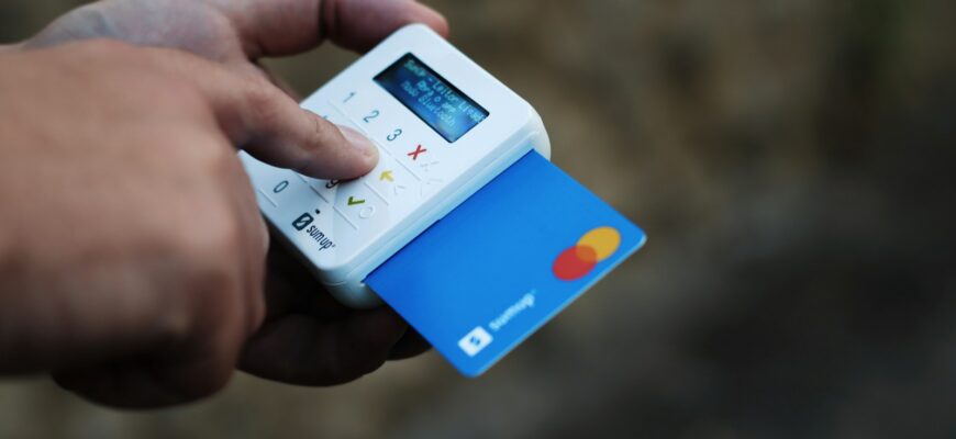 a hand holding a credit card and a cell phone