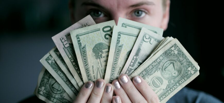 person holding fan of U.S. dollars banknote