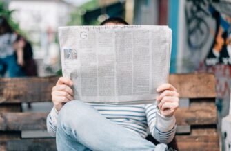 man sitting on bench reading newspaper